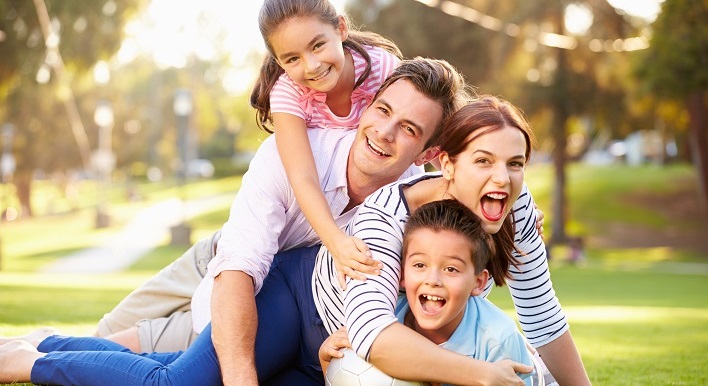 family lying on grass in park together